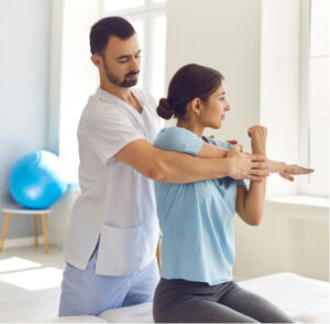 A physiotherapist guiding a woman through a shoulder stretch during treatment, supporting mobility and pain relief for shoulder bursitis.