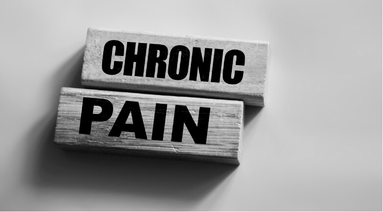 Black and white image of wooden blocks spelling “CHRONIC PAIN,” symbolising the persistent nature of pain and its relevance in pain science discussions.