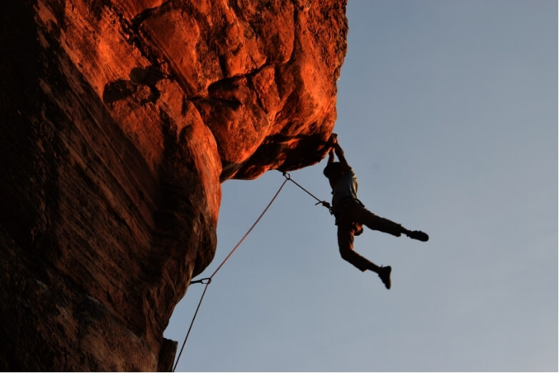 Climber gripping rock with visible hand strain, illustrating finger pulley injury risk in rock climbing.