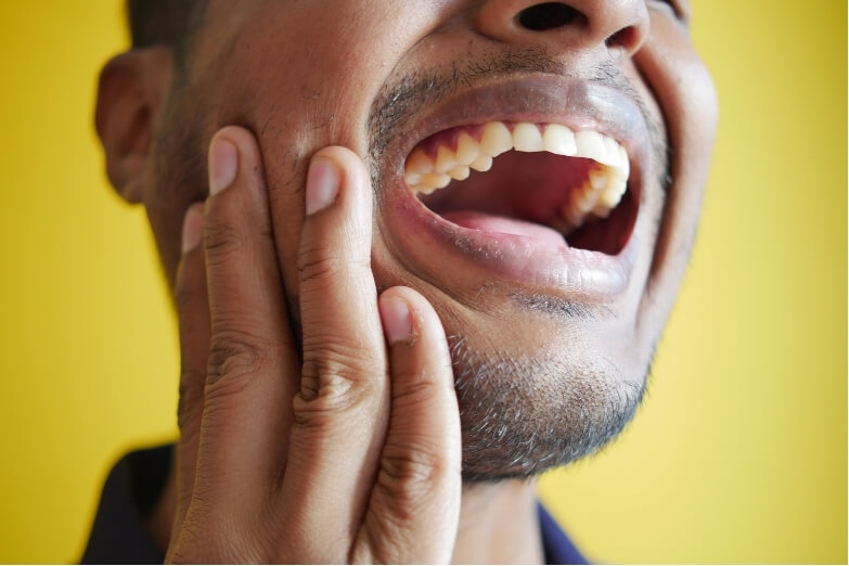 Man experiencing intense jaw pain, a common symptom of Temporomandibular Disorder (TMD).