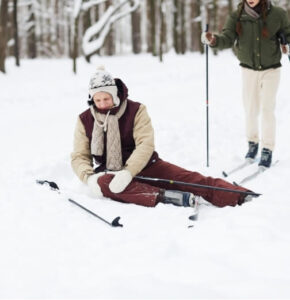 Person sitting in snow after a skiing fall, possibly experiencing a winter sports injuries.
