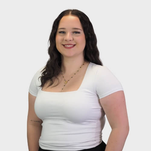Holly Davies, Administrator M Physio, smiling in a professional headshot, wearing a white top against a plain white background.