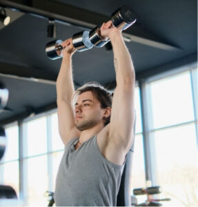 Man lifting weights to improve posture and strength, helping manage driving and low back pain.