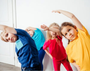 Children doing side stretches in a physio session, promoting flexibility and joint health.