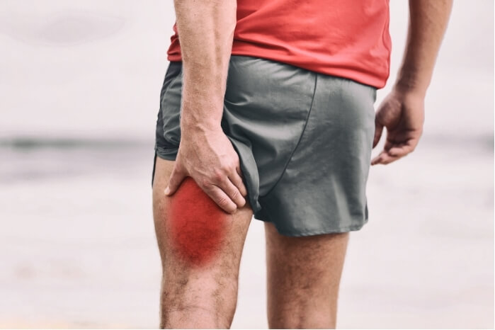 Man clutching back of thigh with visible pain – highlighting the need for effective hamstring tear treatment