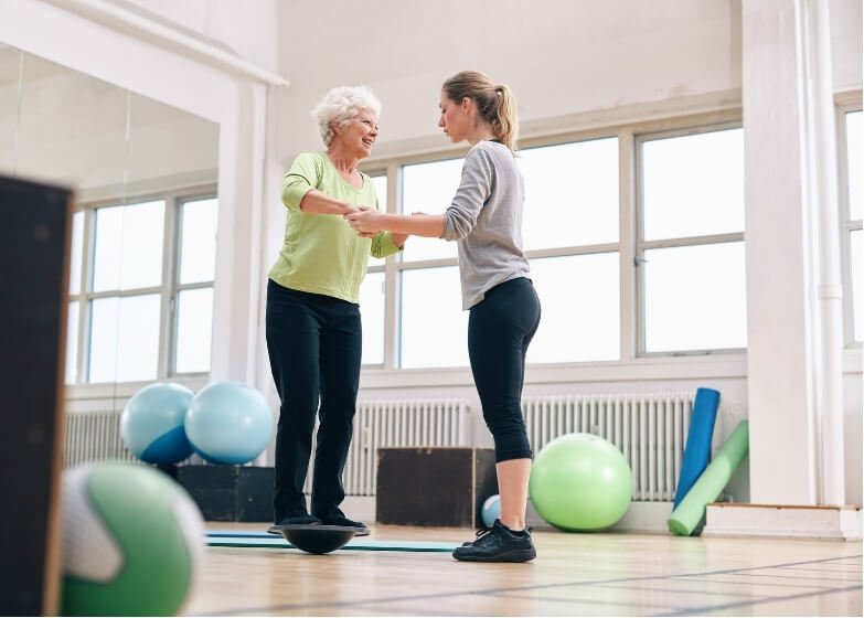 Physiotherapist assisting older adult with stability exercises for balance training for falls prevention