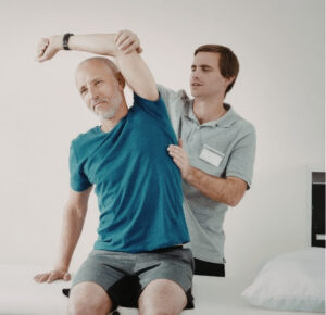 Physiotherapist assisting patient with frozen shoulder treatment exercises