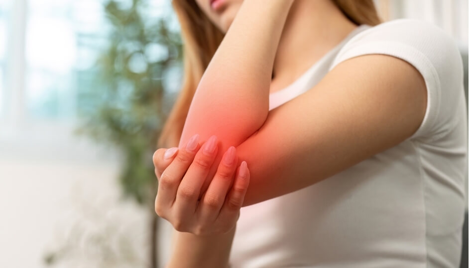 Person holding a painful elbow demonstrating persistent symptoms that may be linked to underlying elbow pain causes.