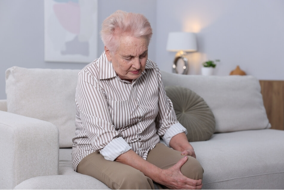 Older adult holding a painful knee, highlighting the impact of ongoing chronic pain.