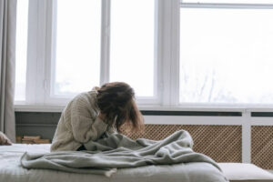Person sitting on a bed experiencing chronic pain and discomfort that is affecting daily activities.