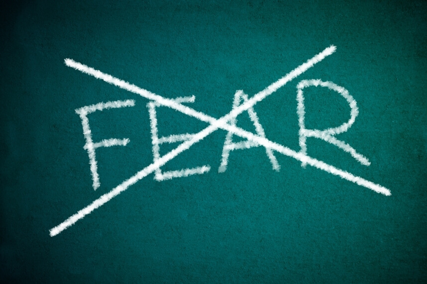 The word 'fear' crossed out on a chalkboard, representing overcoming the fear of movement to support recovery from pain.