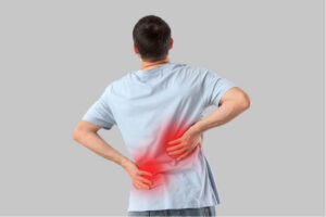 Person holding their lower back, illustrating fear of movement associated with persistent back pain.
