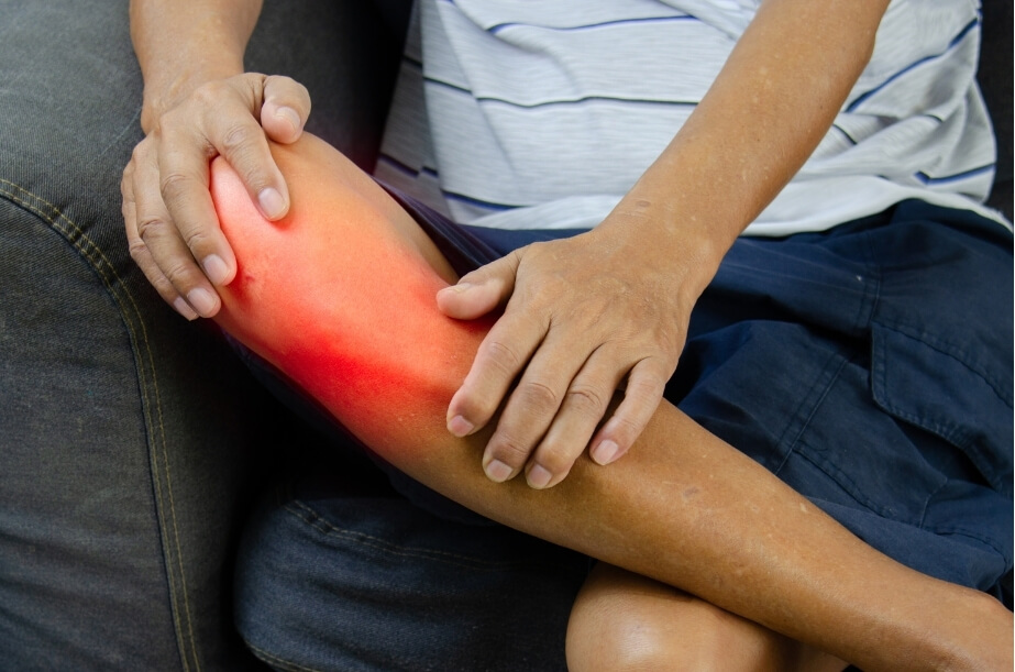 Person holding a painful knee, demonstrating symptoms commonly associated with patellar tendinopathy.