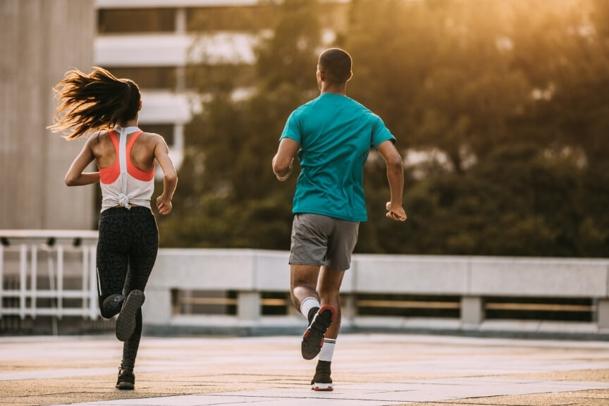 Two people running outdoors while monitoring their response to exercise and rehabilitation loading.