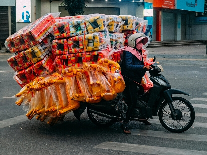 Motorbike rider carrying a very large load of goods, illustrating the relationship between physical load and capacity during rehabilitation.