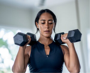 Woman performing a dumbbell exercise as part of strength training to build physical capacity.