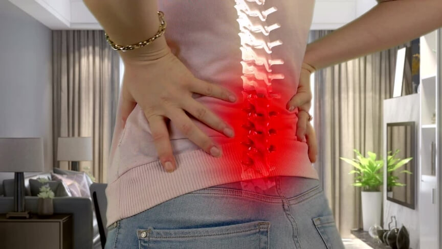 Person holding their lower back with an illustrated spine and red highlighted area representing lower back pain and pain perception.