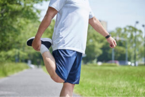 Person standing outdoors and stretching their quadriceps before exercise while managing tendon pain.